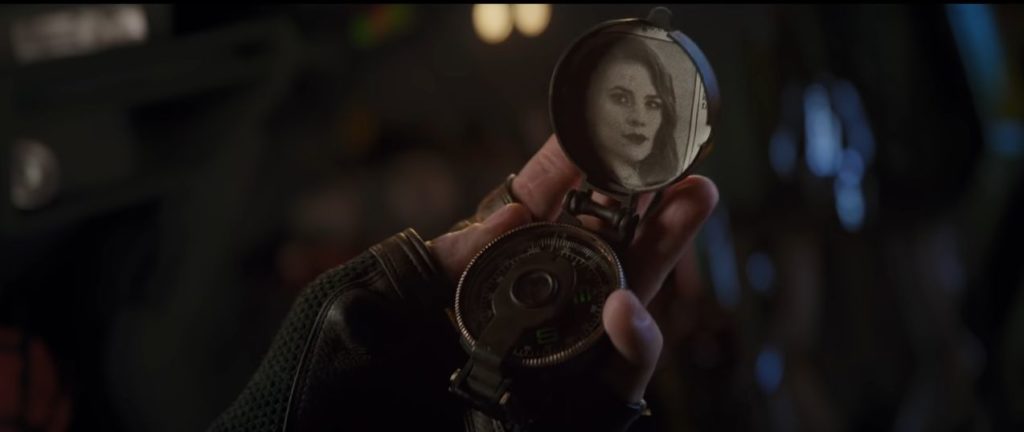 Captain America holding a locket with a photo of a young Peggy Carter in his hands